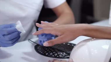 Güzellik uzmanının ellerine yakın plan temizleme yastığıyla tırnak temizleme.