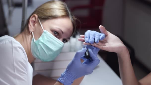 Mestre de prego na máscara faz a manicura da mulher no salão — Vídeo de Stock