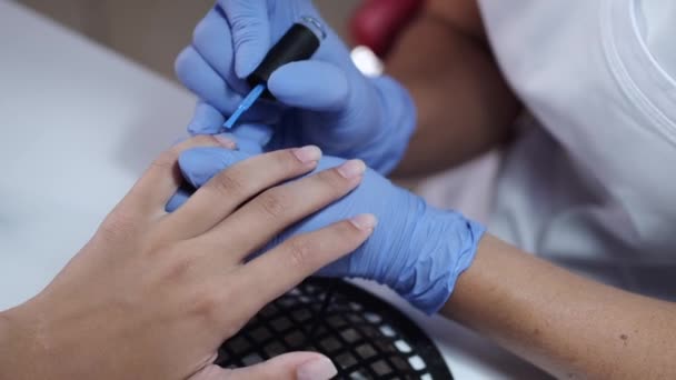 Close-up de mãos esteticistas fazendo manicure azul para o cliente — Vídeo de Stock