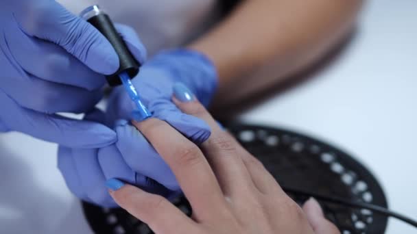 Primer plano de manos esteticistas haciendo manicura azul para el cliente — Vídeo de stock