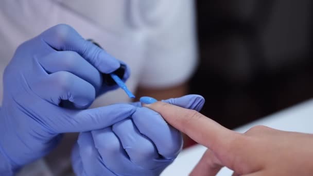 Close-up de mãos esteticistas fazendo manicure azul para o cliente — Vídeo de Stock