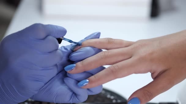 Κοντινό πλάνο των αισθητικών χεριών κάνοντας μπλε μανικιούρ για τον πελάτη — Αρχείο Βίντεο