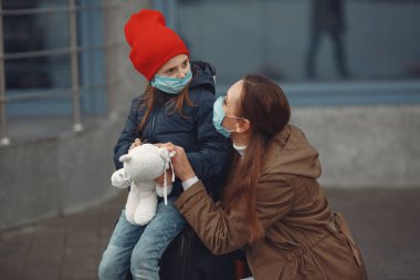 Kızıyla birlikte solunum cihazına bağlı Avrupalı bir anne binanın yanında duruyor. Ebeveyn kendini virüsten korumak için çocuğuna koruyucu maske takmayı öğretiyor.