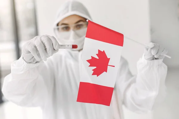 The scientist in coverall suit with a coronavirus sample and Canadian flag — Stock Photo, Image
