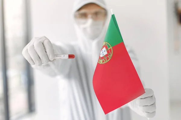 Ученый в комбинезоне с образцом коронавируса и португальским флагом Стоковое Изображение