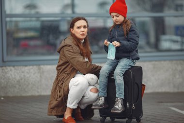 Kızıyla birlikte solunum cihazına bağlı Avrupalı bir anne binanın yanında duruyor. Ebeveyn kendini virüsten korumak için çocuğuna koruyucu maske takmayı öğretiyor.