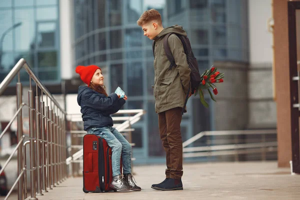 Un garçon se tient debout avec un tas de tulipes et donne des fleurs à une petite fille — Photo