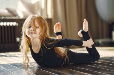 Spor kıyafetli küçük kız jimnastik yapıyor.