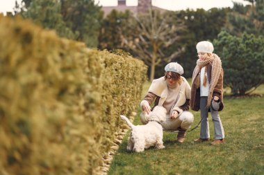 Anne ve kızı bir köpekle yürür.