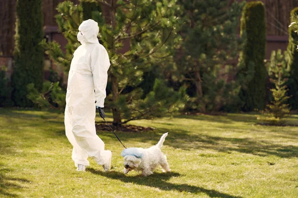 Mujer con traje protector paseando con un perro — Foto de Stock