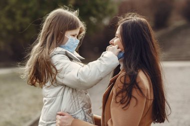 Anne ve kızı maskelerle dışarı çıkıyorlar.