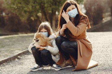 Anne ve kızı maskelerle dışarı çıkıyorlar.