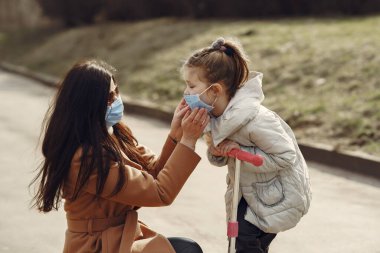 Anne ve kızı maskelerle dışarı çıkıyorlar.