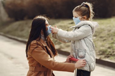 Anne ve kızı maskelerle dışarı çıkıyorlar.