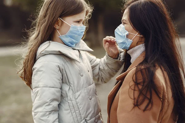 Mor med dotter går utanför i masker — Stockfoto