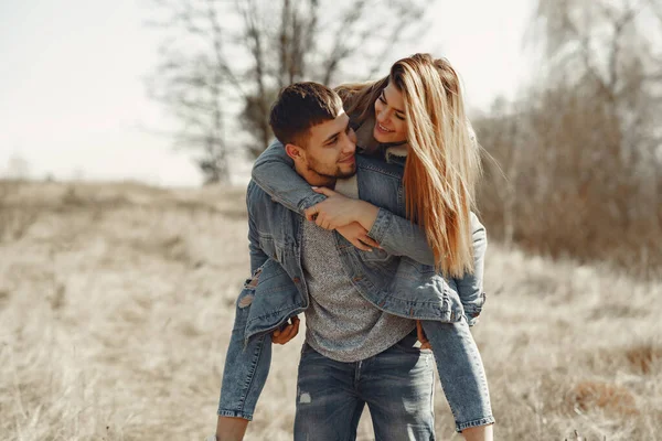 Casal bonito em uma roupa de calça em um campo de primavera — Fotografia de Stock