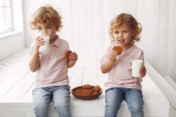 Crianças bonitas comendo biscoitos e bebendo leite — Fotografia de Stock