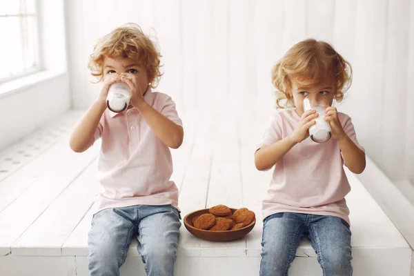 Lindos niños comiendo galletas y bebiendo leche — Foto de Stock