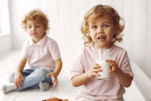 Słodkie dzieci jedzące ciasteczka i pijące mleko — Zdjęcie stockowe