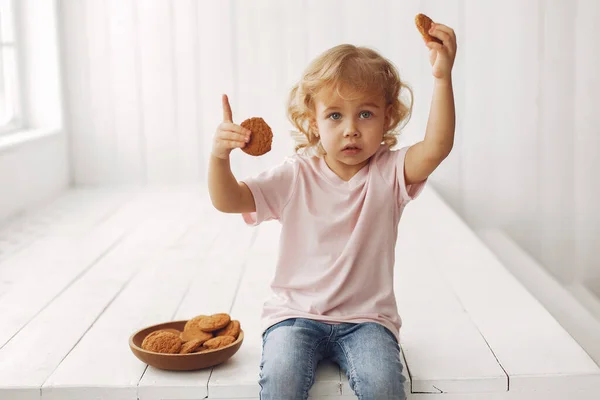 Carino bambina seduta in uno studio e mangiare biscotti — Foto Stock