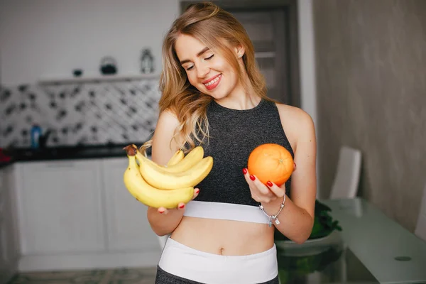 Menina de esportes em uma cozinha com frutas — Fotografia de Stock