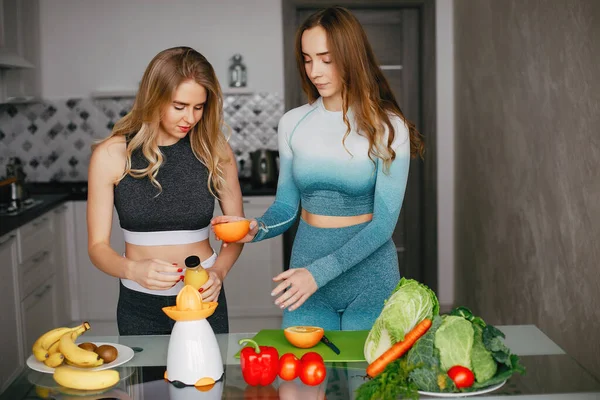 Zwei Sportlerinnen in einer Küche mit Gemüse — Stockfoto