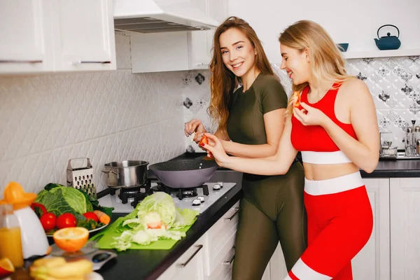 Dois esportes menina em uma cozinha com legumes — Fotografia de Stock