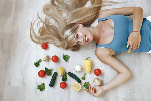 Menina bonita e desportiva em uma cozinha com um legumes — Fotografia de Stock