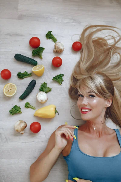 Menina bonita e desportiva em uma cozinha com um legumes — Fotografia de Stock