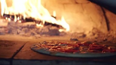 Kesik gözlü insan pizzayı mutfakta fırına koyar.