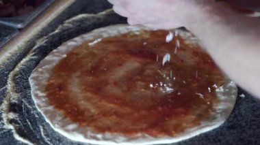 Restoranda pizzanın üstüne peynir koyan şeflerin yakın çekimi.