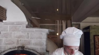 Beyaz üniformalı şef İtalyan restoranında pizza yapıyor.