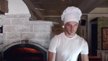 Beyaz üniformalı şef İtalyan restoranında pizza yapıyor.