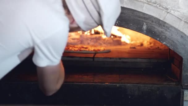 Шеф-повар кладет пиццу в духовку для приготовления пищи в итальянском ресторане — стоковое видео