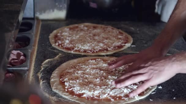 Fechar-se de mãos de chefs pondo o queijo na pizza no restaurante — Vídeo de Stock