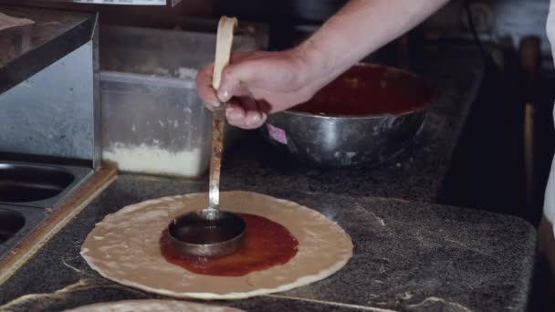 Kucharz przycięty widok wylewa sos pomidorowy na ciasto — Wideo stockowe