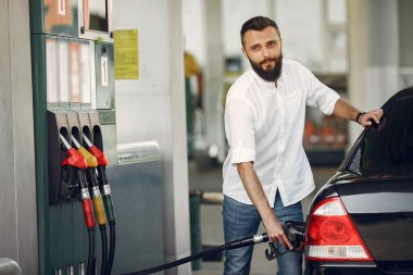 Yakışıklı adam bir depo arabaya benzin dolduruyor.