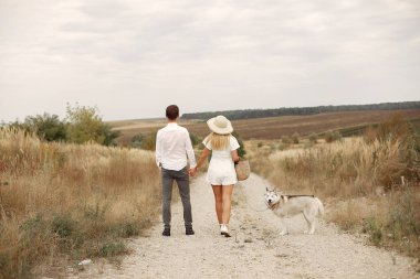 Sonbahar tarlasında bir çift köpekle oynuyor.