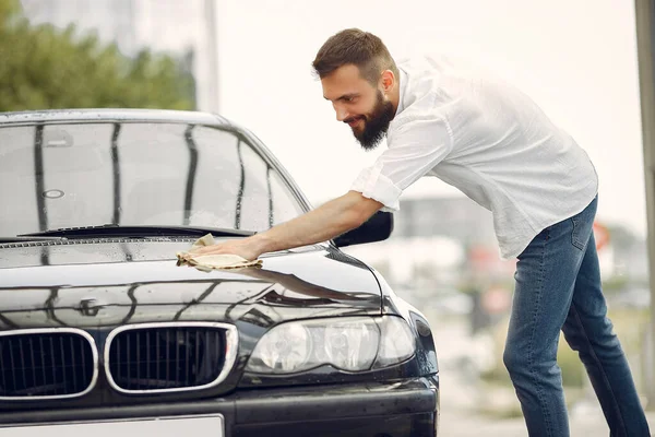 Pria berbaju putih menyeka mobil di tempat cuci mobil — Stok Foto