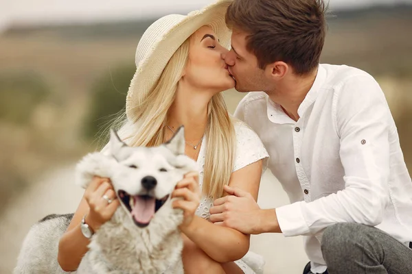 Couple in a autumn field playing with a dog — Stock Photo, Image