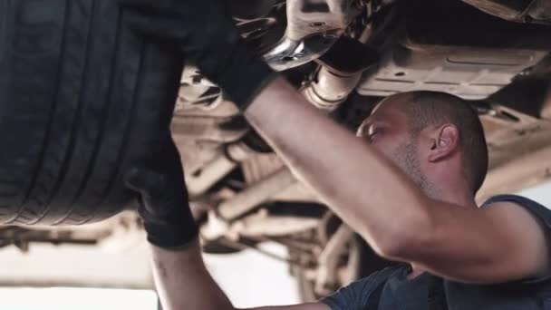 Servis merkezinde arabanın altında çalışan eldivenli tamirci. — Stok video