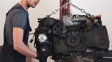 Eldivenli işçi, servis merkezinde arabanın motorunu çıkarıyor.