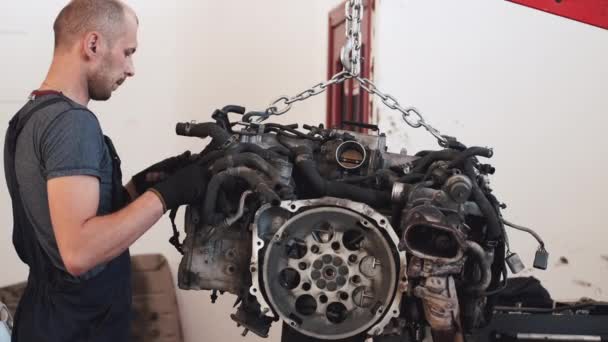 El hombre pone el motor en el coche después de la reparación en el garaje — Vídeos de Stock