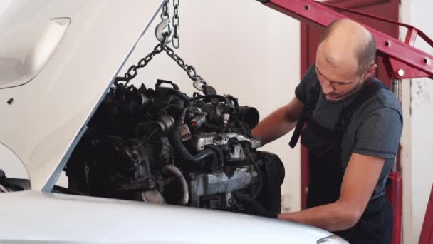Человек кладет мотор в машину после ремонта в гараже — стоковое видео