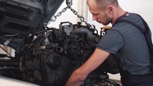 El hombre pone el motor en el coche después de la reparación en el garaje — Vídeos de Stock