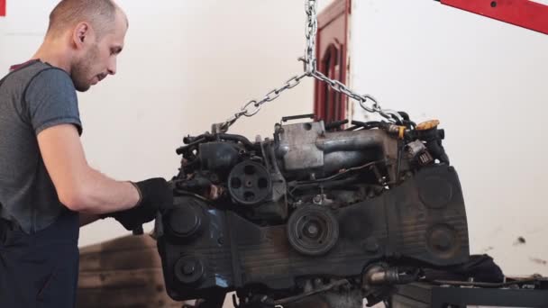 Работник в перчатках снимает двигатель автомобиля в сервисном центре — стоковое видео