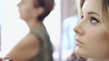 Sanatçı, müşterilerin göz kapaklarına altın gölgeler sürüyor.