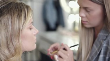 Makyaj sanatçısı kuaförde müşterilerin yüzüne kozmetik uyguluyor