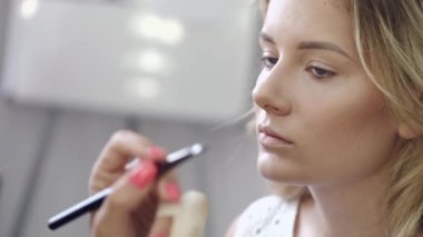 Makyaj sanatçısı kuaförde müşterilerin yüzüne kozmetik uyguluyor