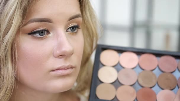 Rostro de mujer joven y paleta con sombras de ojos en el salón — Vídeo de stock